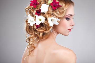 Beautiful girl on a grey with varicoloured flowers  in hairs