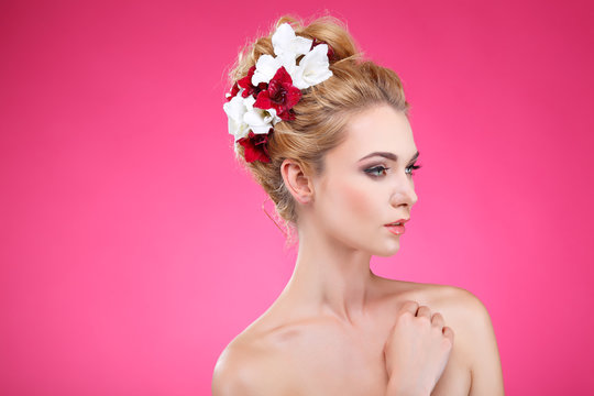 Beautiful girl on a pink with varicoloured flowers in hairs,