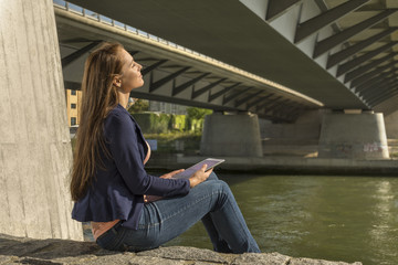 Pretty young woman relaxing at urban riverside