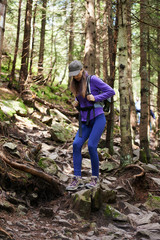 Naklejka na ściany i meble Woman with backpack hiking into the forest