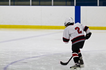 Young child skating and playing ice hockey