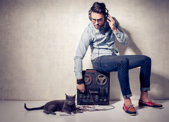 handsome man and cat listening to music on a magnetophone