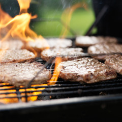 grilling hamburgers on charcoal grill with flames
