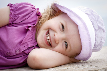 Happy little girl lying on the rock