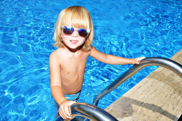 Bambino in piedi su scaletta della piscina