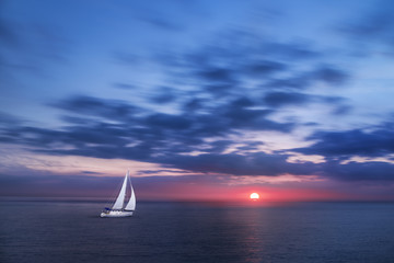 Voilier en Pleine Mer durant un Coucher de Soleil