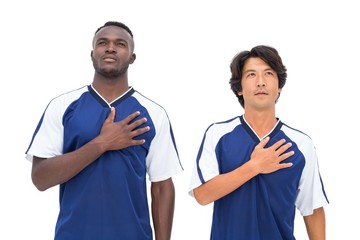 Football players in blue listening to anthem