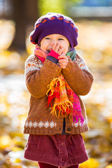 Happy little girl playing in the autumn park