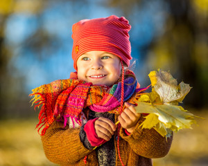 Little girl playing with autumn leaves