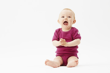 Baby girl sitting against white background.