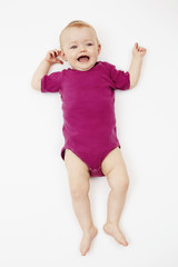 Baby girl lying against white background.