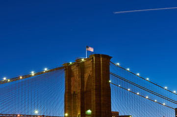 Close up of a pillar of the Brooklyn bridge with flag at night