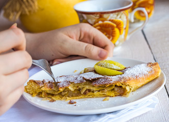 apple strudel on a white plate, hands, eating process