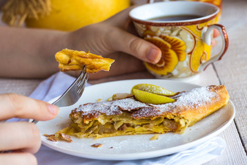 eat apple strudel, hands, on a white wooden board