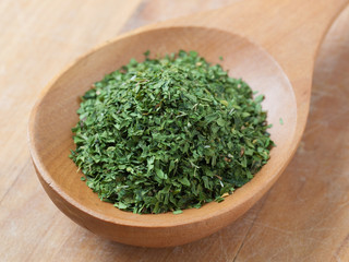 Parsley seasoning in a wooden spoon.