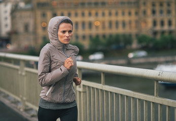 Fitness young woman jogging in rainy city