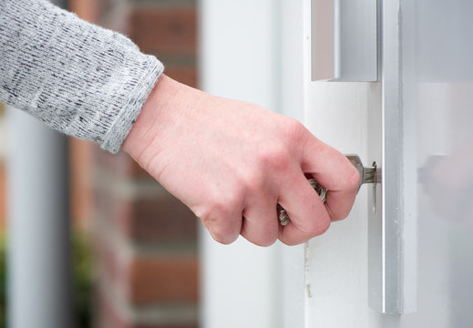 Female hand inserting key in door