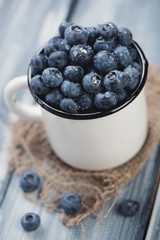 Enameled cup with ripe blueberries, close-up