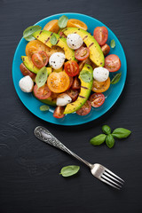 Vegetable salad with grilled avocado, black wooden surface