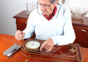 Senior man repairing wall clock