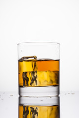 Whisky splashing in glass on a white background