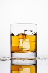 Whisky splashing in glass on a white background