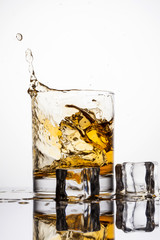 Whisky splashing in glass on a white background
