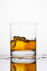 Whisky splashing in glass on a white background