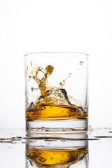 Whisky splashing in glass on a white background