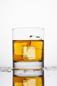 Whisky splashing in glass on a white background