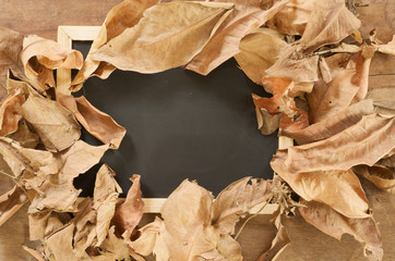 blackboard and dried leaf on wooden background