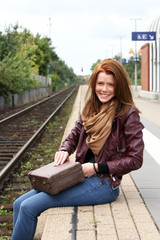 Obraz na płótnie Canvas junge Frau wartet am Bahnsteig auf Ihren Zug