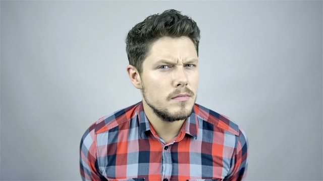Handsome man expressing doubt over green background