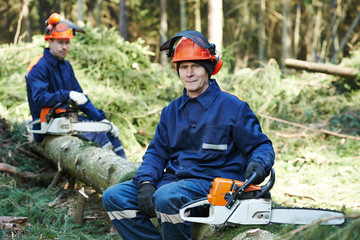 Lumberjack worker with chainsaw in the forest