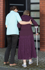 Nurse helping woman walking with crutches