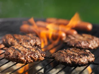  hamburgers and hotdogs cooking on grill outdoors © Joshua Resnick