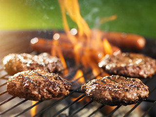 hamburgers and hotdogs cooking on flaming grill - obrazy, fototapety, plakaty