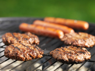 hamburgers and hotdogs cooking on grill outdoors