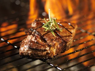 Photo sur Plexiglas Grill / Barbecue steak with flames on grill with rosemary