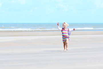 Fototapeta na wymiar Little happy girl playing on the beach