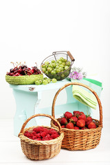 Fototapeta na wymiar Fresh berries in baskets on white wall background
