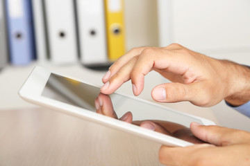 Man working on tablet on wooden background closeup