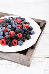 Iced berries on plate, on color wooden background