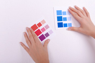 Woman choosing color for wall from swatches in room