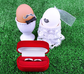 Bride and bridegroom eggs in egg cups on green background