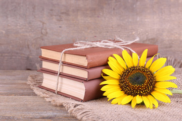 Books and sunflower on wooden table on wooden wall background