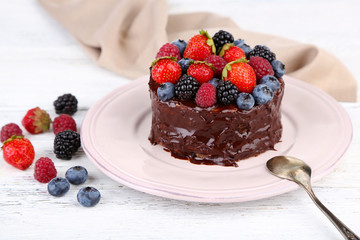 Tasty chocolate cake with different berries, on wooden table