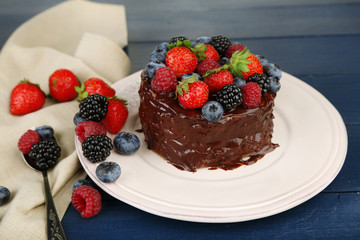 Tasty chocolate cake with different berries, on wooden table