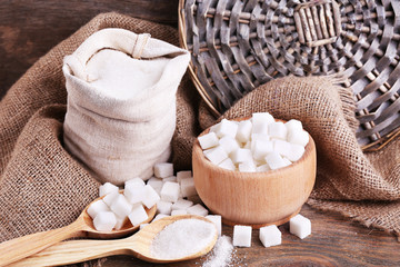 Fototapeta na wymiar Refined sugar in bag and bowl on wooden background