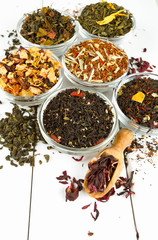 assortment of dry tea in glass bowls on wooden surface